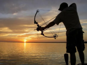 Setting Sun While Man Takes Aim While Bowfishing